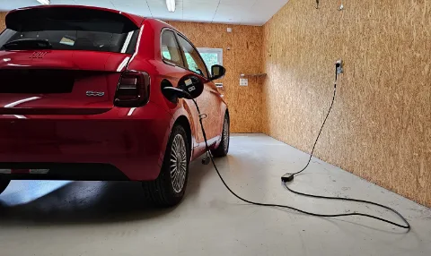 Voiture électrique reliée à un point de recharge dans un garage