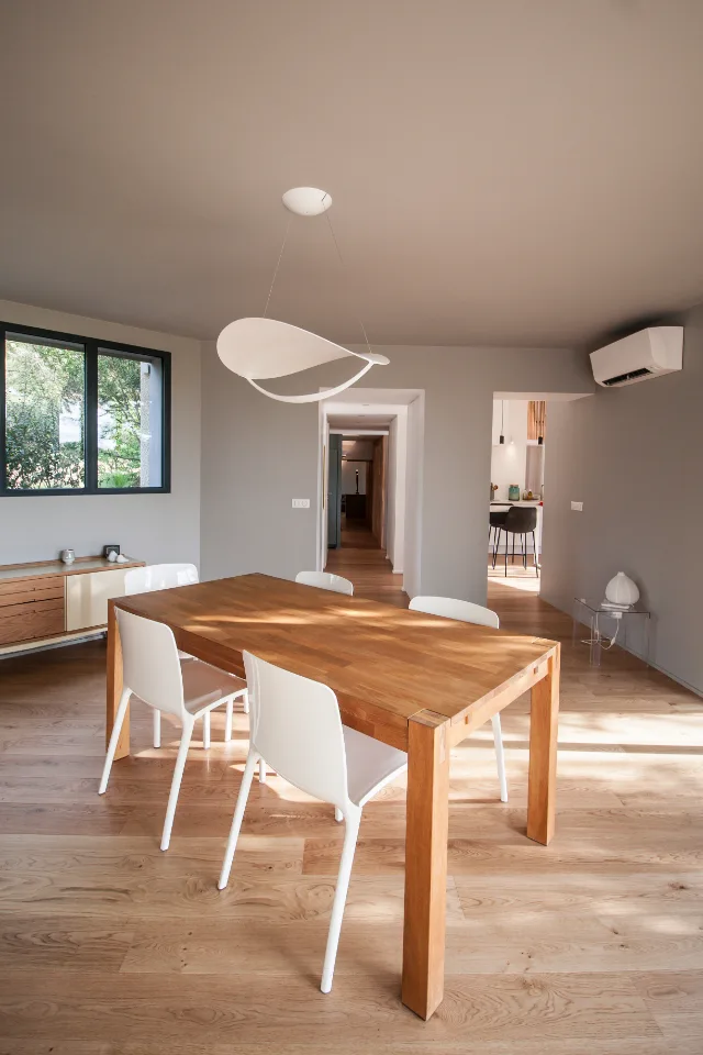 Salle à manger avec table en bois, suspension blanche en ruban et climatiseur mural