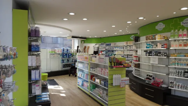 Pharmacie aux rayonnages muraux courbes verts et blancs, faux plafond arrondi et spots encastrés