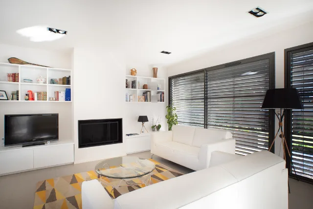 Séjour blanc avec cheminée encastrée, canapés blancs, spots orientables et lampadaire noir