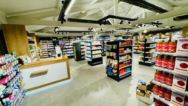 Espace de vente aux rayonnages garnis, comptoir éclairé en pied et rails de spots noirs