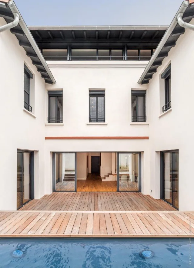 Cour à façade blanche, terrasse en bois et piscine