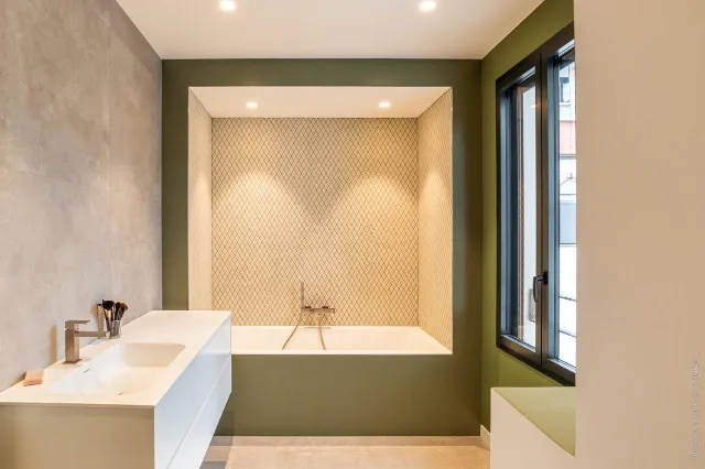 Salle de bain vert olive, baignoire en niche de mosaïque éclairée par deux spots encastrés