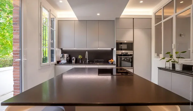 Cuisine grise à îlot sombre, ruban LED sous meubles hauts, gorge lumineuse et spots encastrés