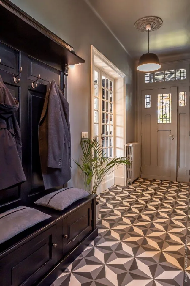 Entrée avec vestiaire noir à patères, carrelage à motif 3D et suspension dôme noire allumée