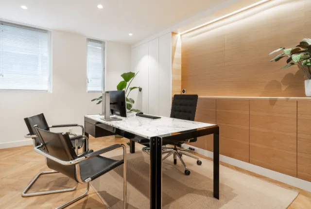 Bureau à plateau effet marbre, fauteuils cuir et chrome, mur plaqué chêne éclairé par ruban LED